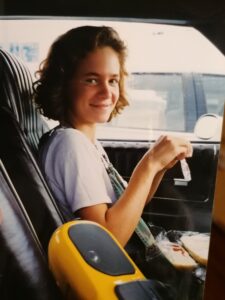 junge Frau am Steuer eines Autos mit gelben Kassettenrekorder