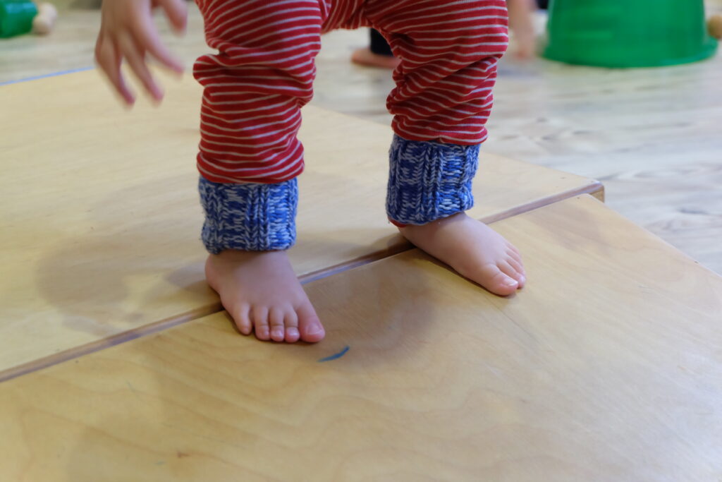 Füße eines Kindes auf der Schwelle des Podests zum Rutschkeil.