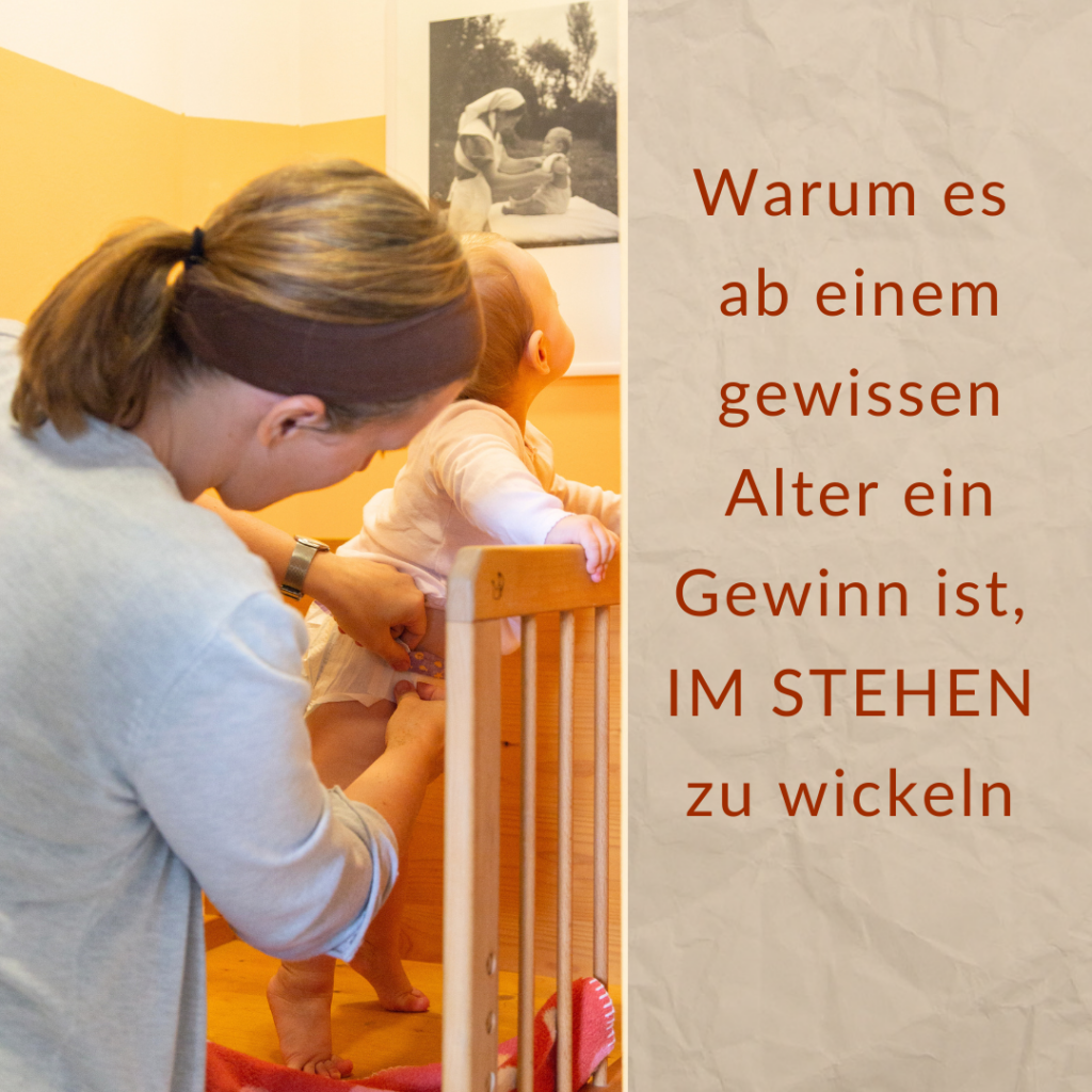 Eine Frau wickelt ein Kleinkind im Stehen auf einem Pikler-Wickelaufsatz